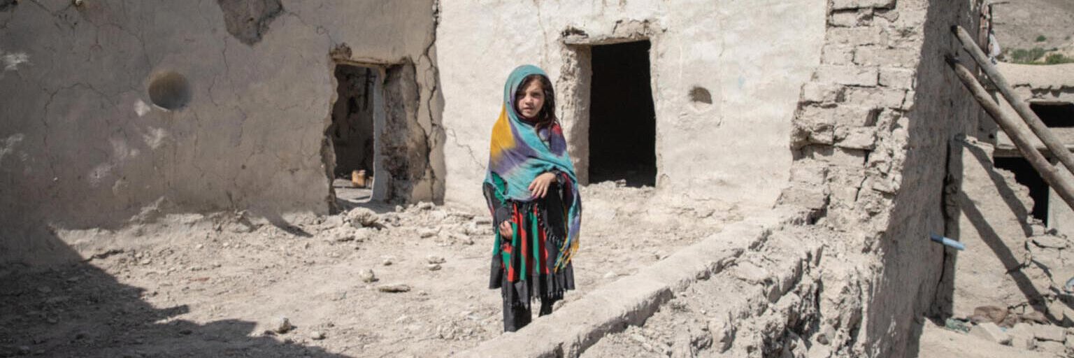Naghma steht im vom Erdbeben zerstörten Haus in Afghanistan.