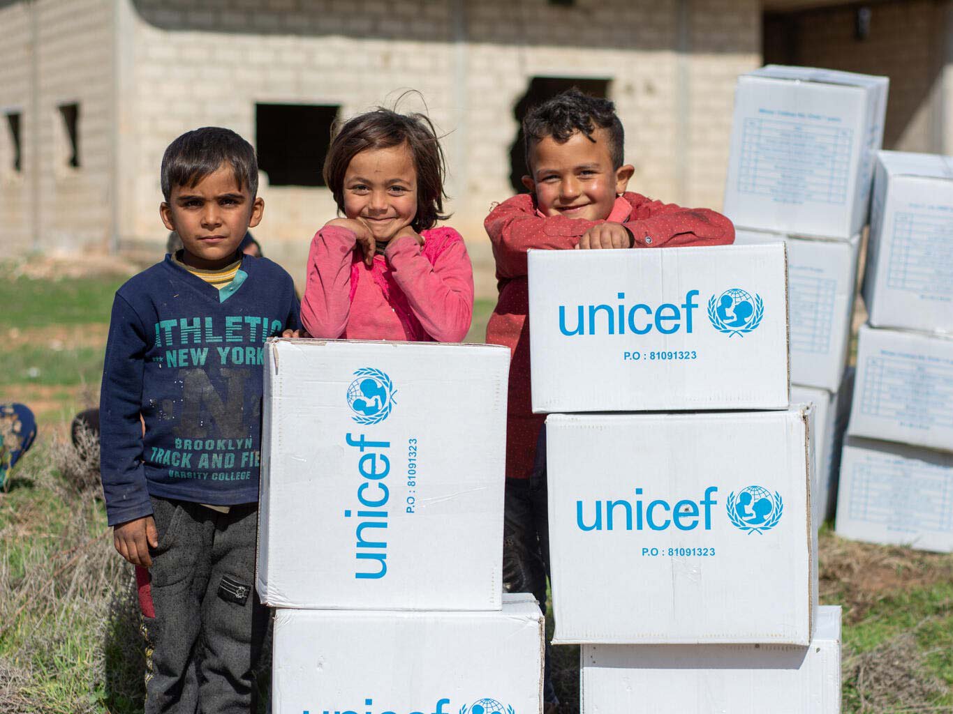 Kinder aus Syrien hinter Boxen voller Hilfsgüter.