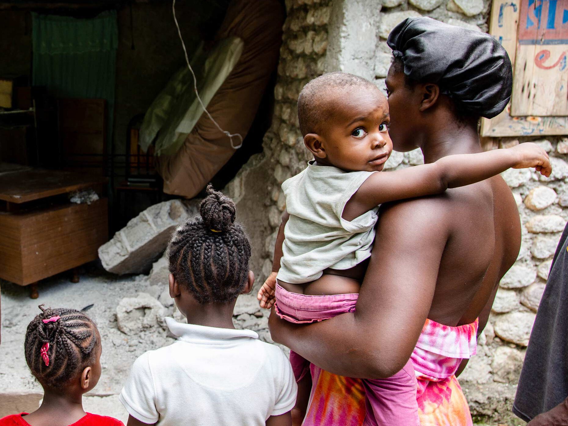 Familie in Haiti vor ihrem zerstörten Zuhause nach dem Erdbeben