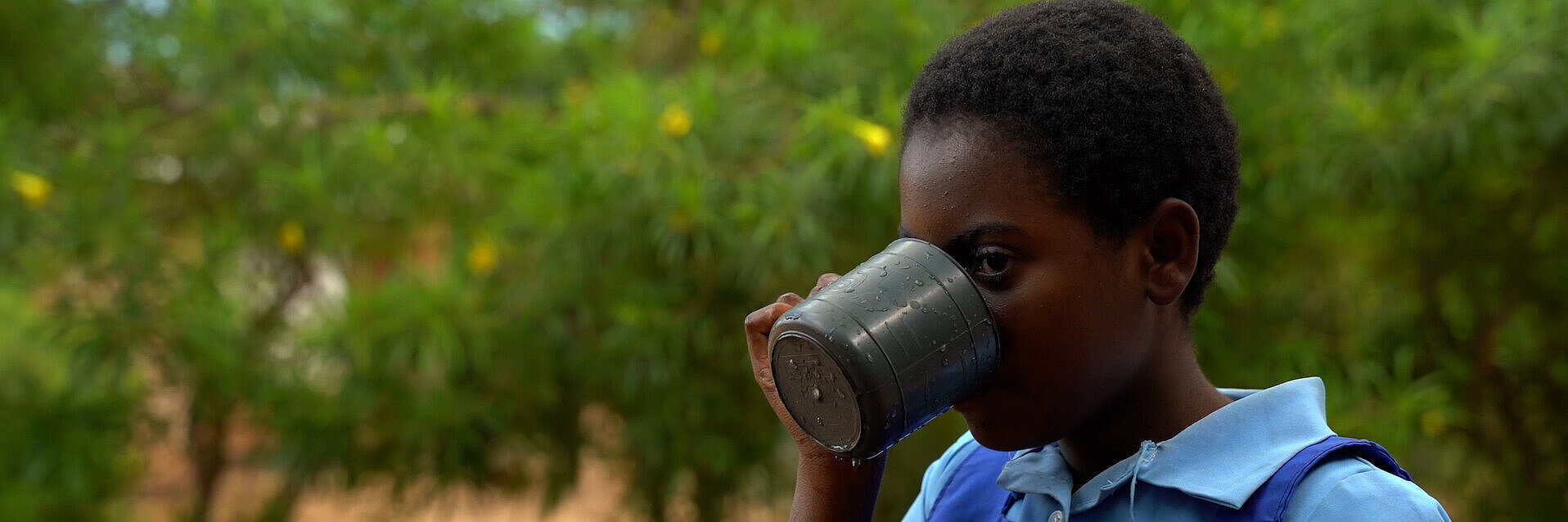 Peace aus Malawi trinkt Wasser aus einem Edelstahlbecher