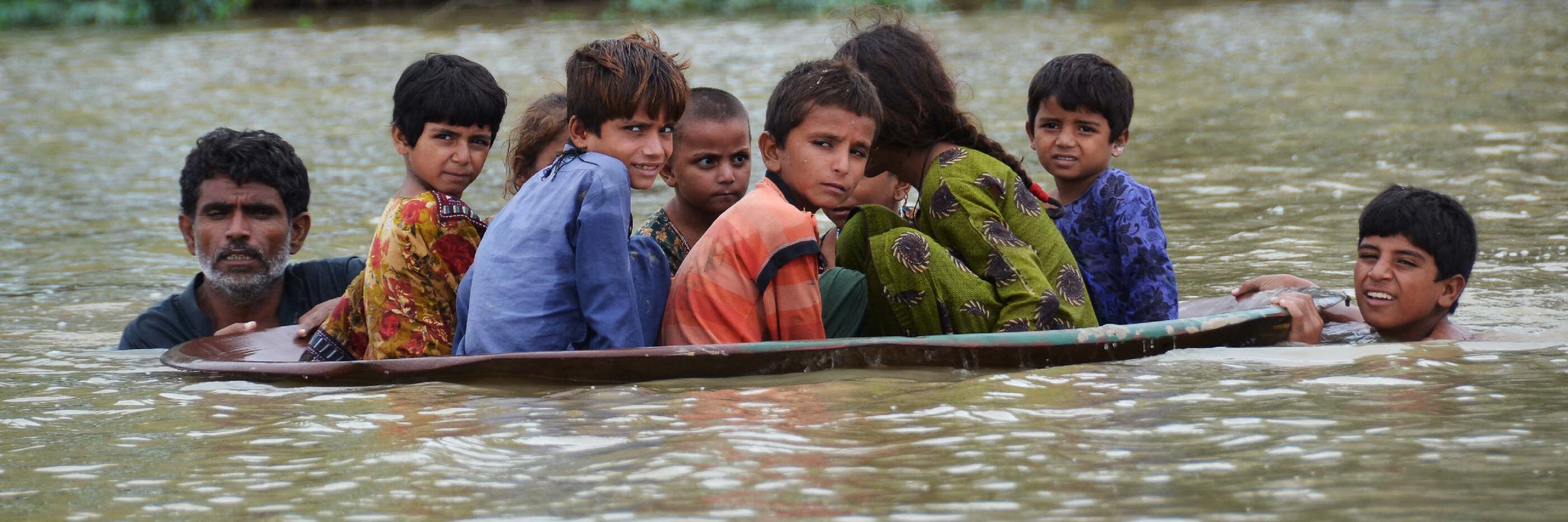 Kinder in einem Boot auf der Flucht der Überschwemmung in Pakistan