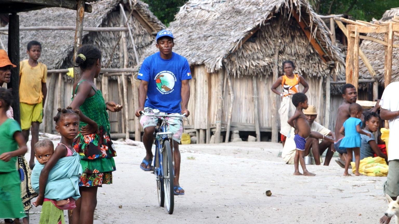 Ein mobiler Gesundheitshelfer fährt mit dem Rad durch ein Dorf.