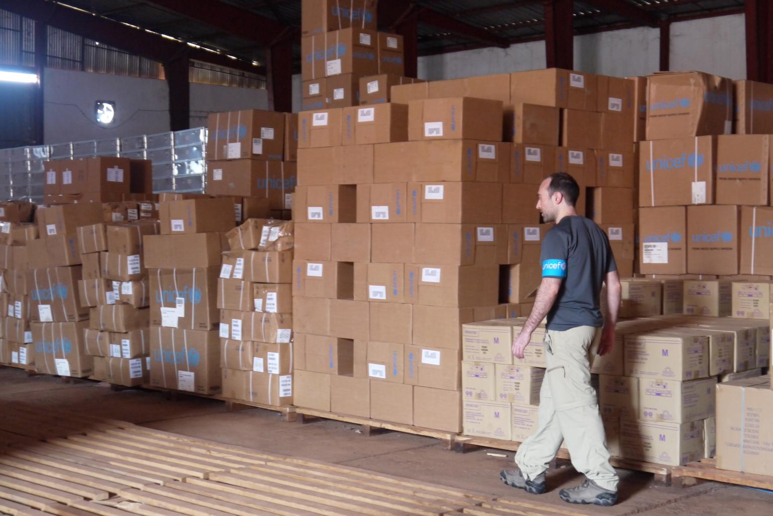 Ein Mitarbeiter von UNICEF steht vor unzähligen Kartons mit Hilfsgütern.