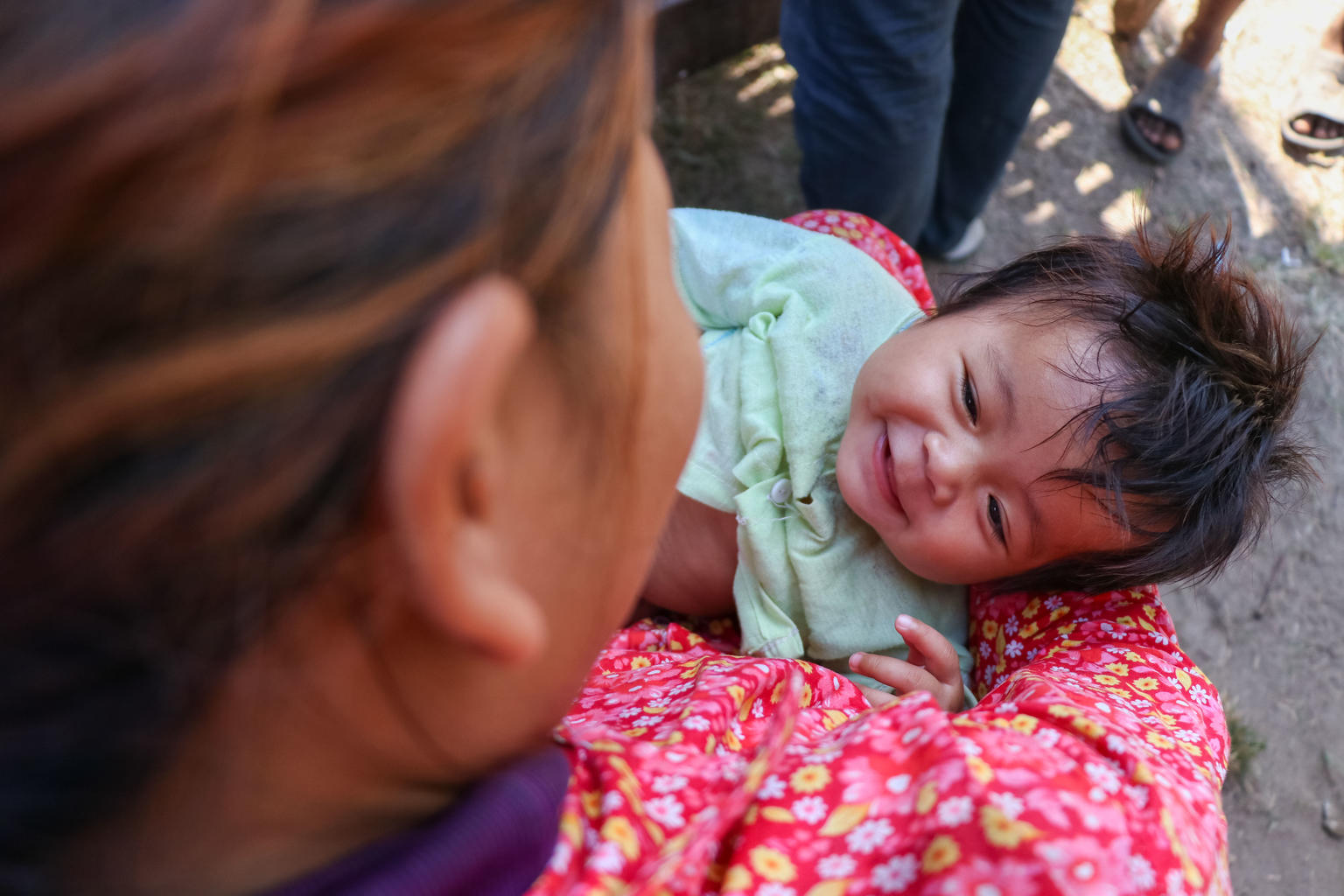Ein Baby lächelt in den Armen seiner, während es auf seine Impfung wartet.