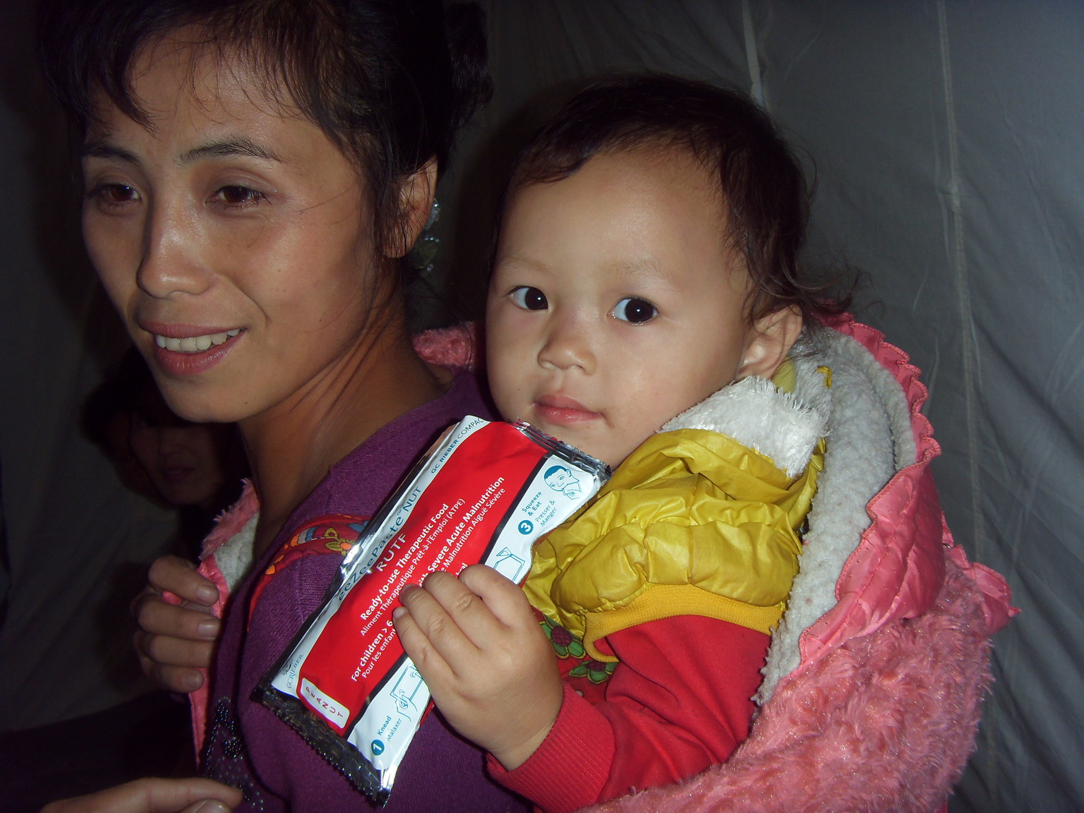 Ein Baby hält eine Packung Erdnusspaste in der Hand.