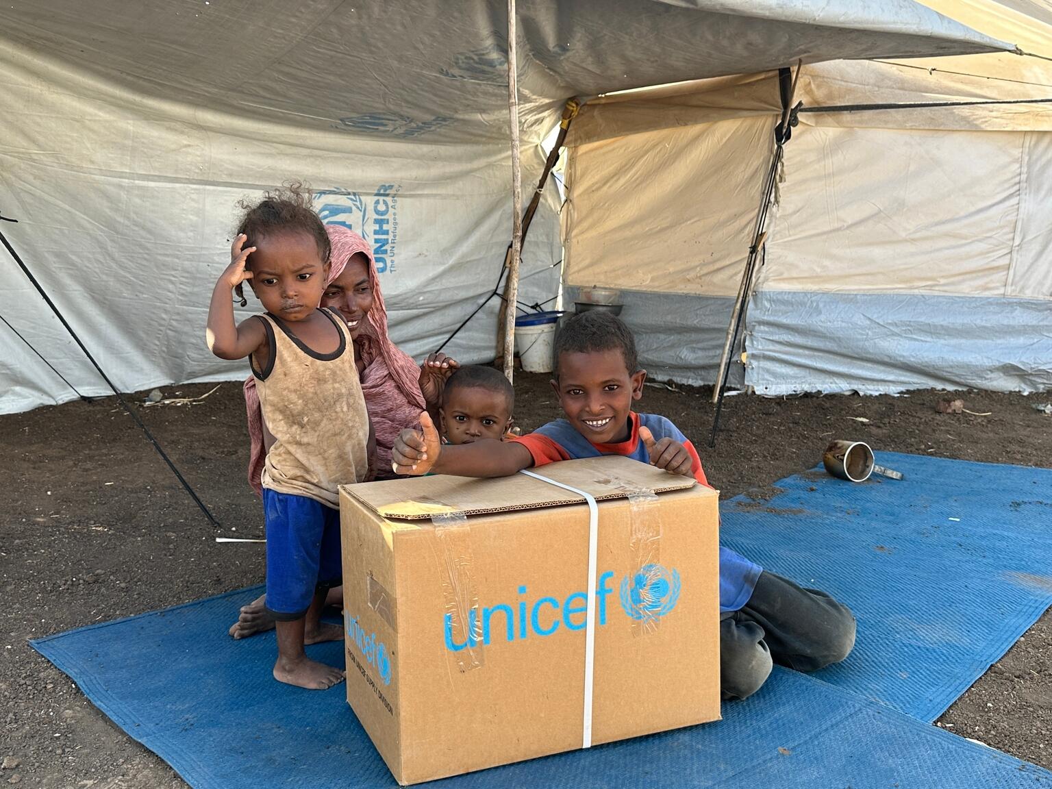Kinder im Sudan sitzen um einen UNICEF-Karton.