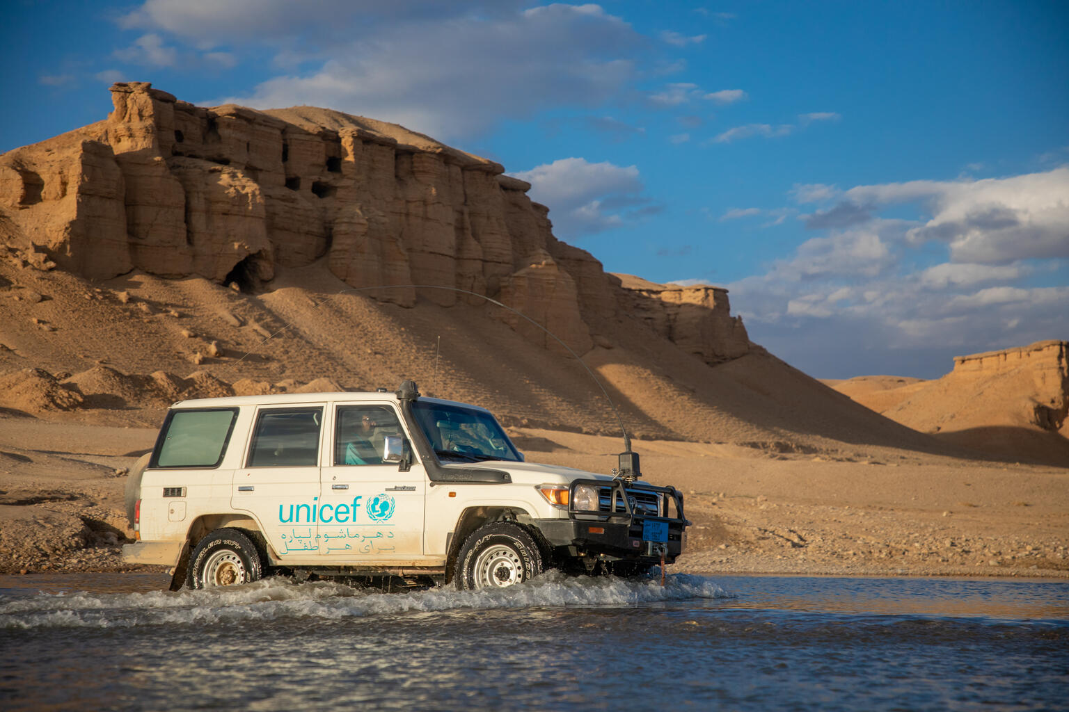 Ein UNICEF Auto fährt durch tiefes Wasser in Afghanistan.