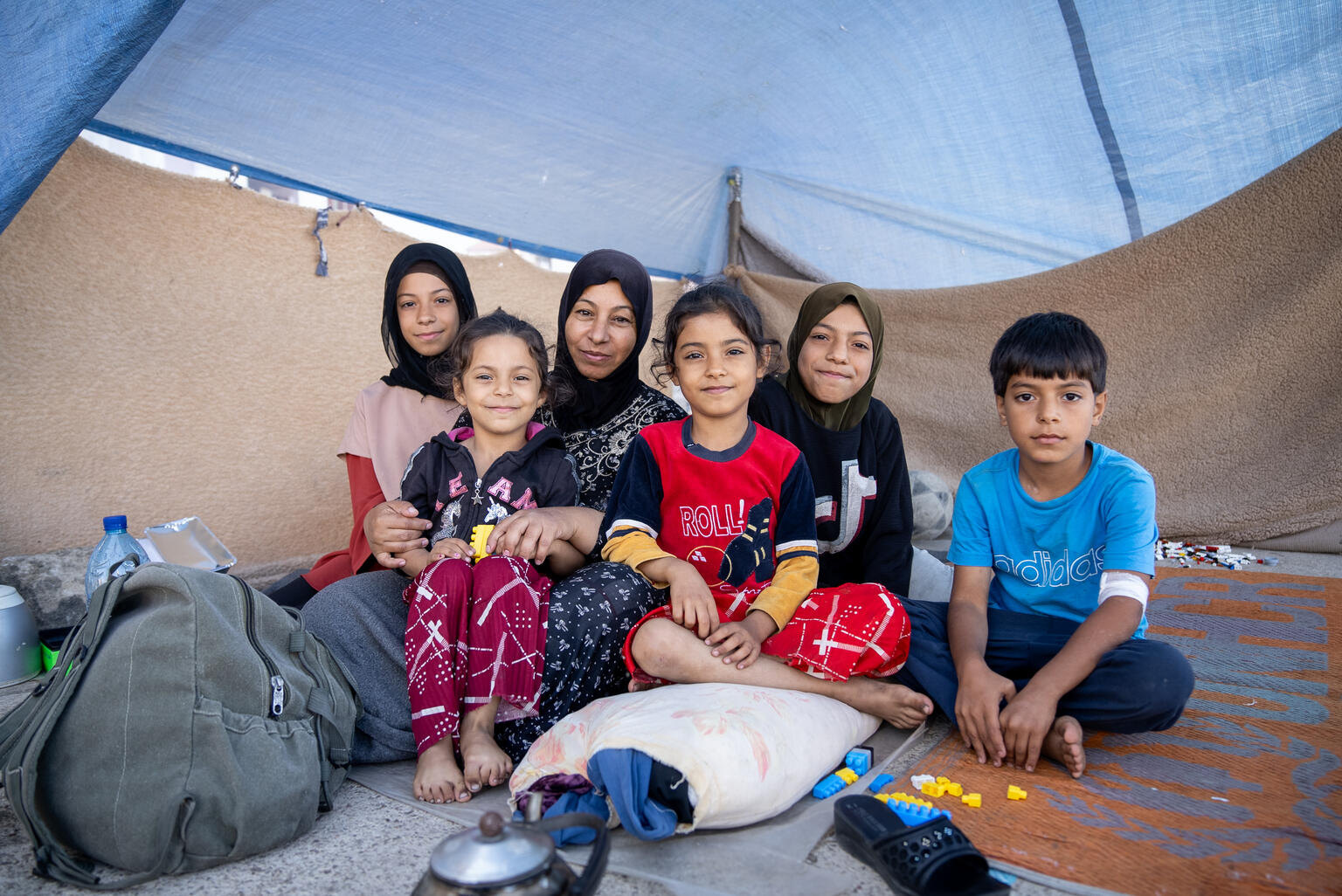 Eine geflüchtete Familie sitzt am Boden ihrer Notunterkunft im Libanon.