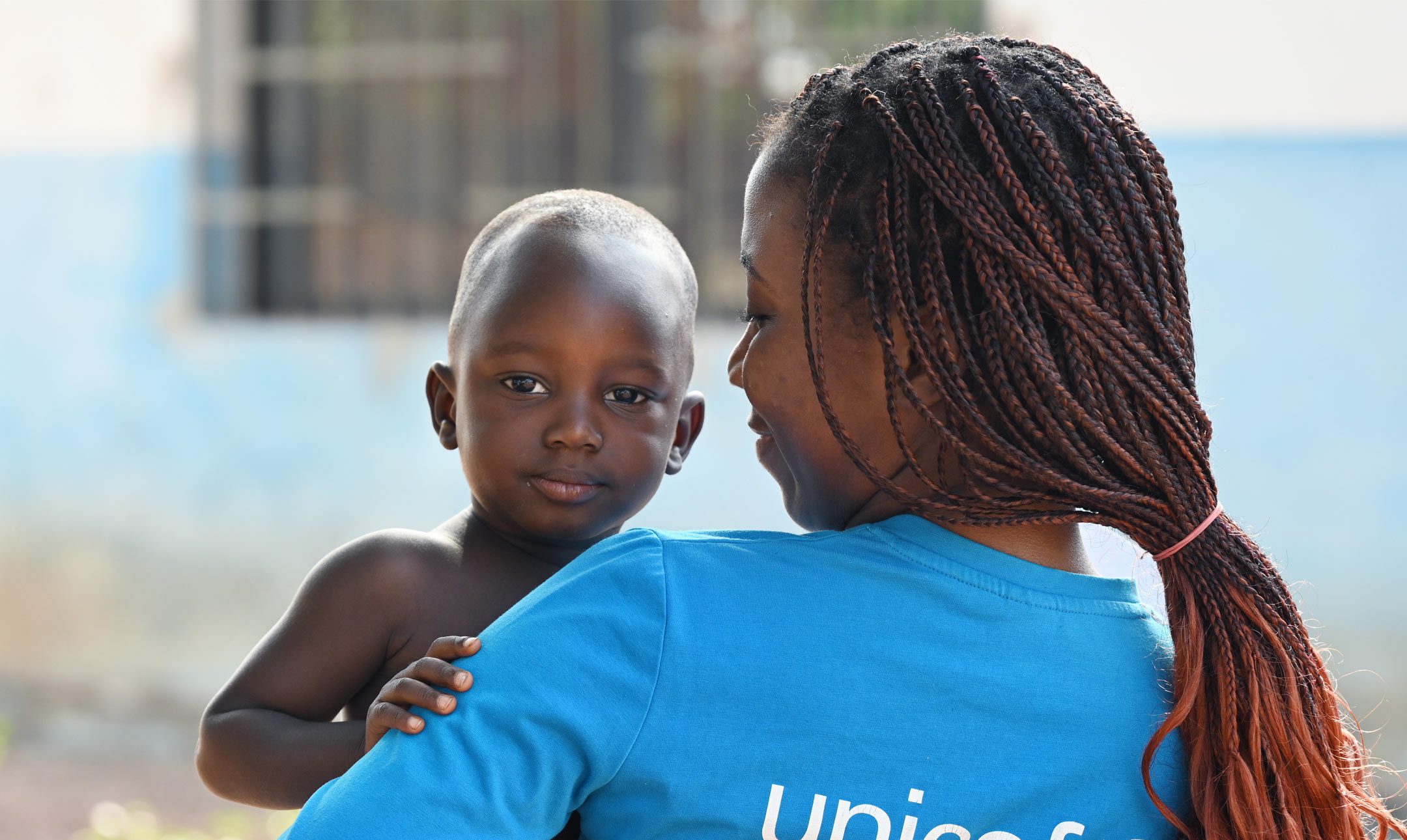 UNICEF MItarbeiterin hält Kind in den Armen
