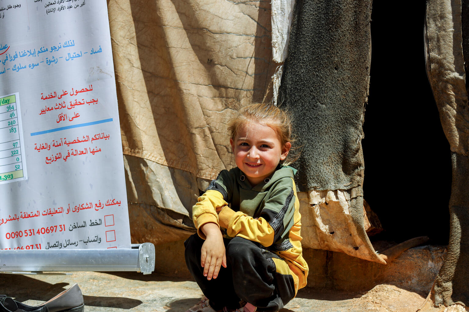 Ein syrisches Kind hockt am Boden einer Flüchtlingsunterkunft.