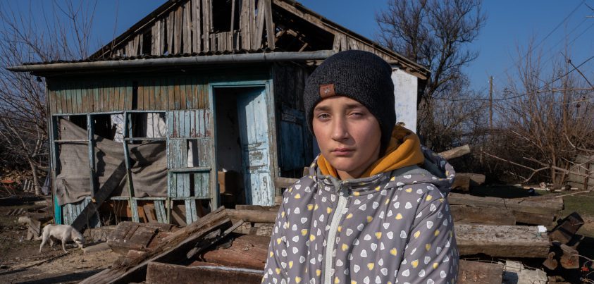 Junge steht vor verfallenem Haus.