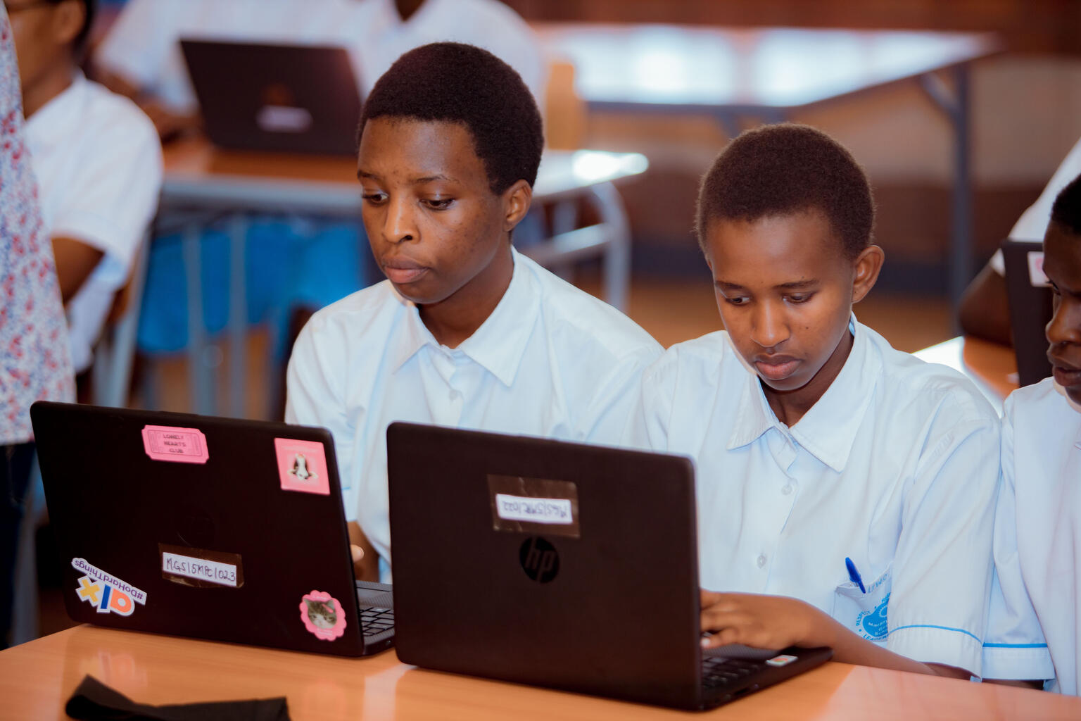 Zwei jugendliche Buben aus Ruanda blicken gebannt in ihre Laptops.