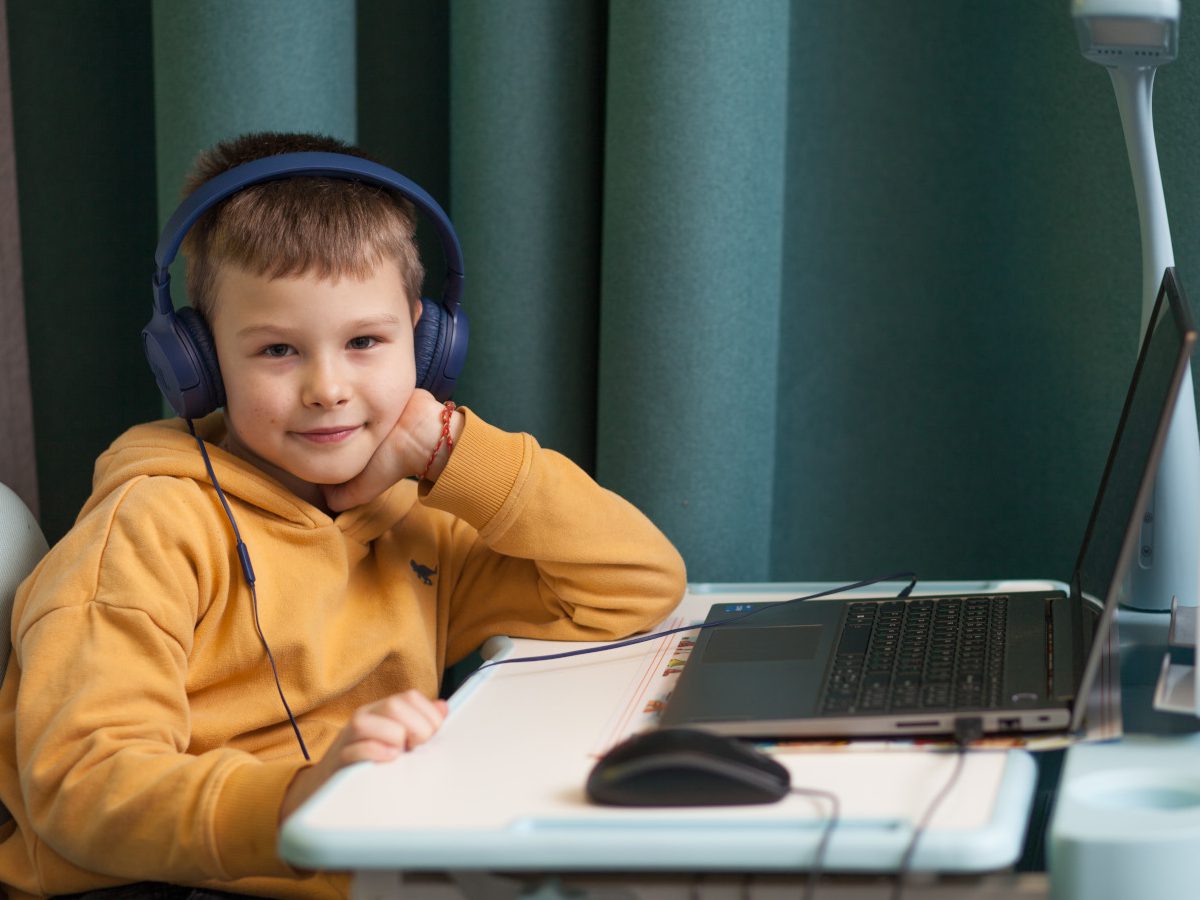 Ein Bub mit Kopfhörern sitzt vor einem Laptop in einem Lernzentrum in der Ukraine.