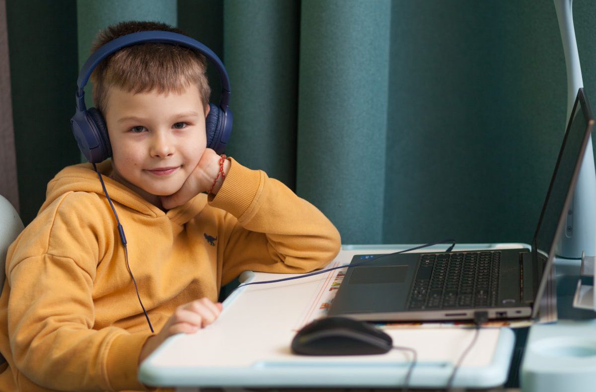 Ein Bub mit Kopfhörern sitzt vor einem Laptop in einem Lernzentrum in der Ukraine.
