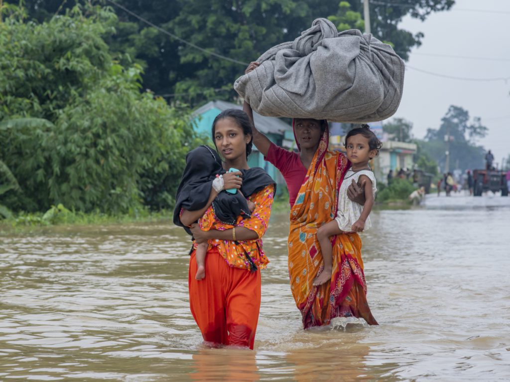Eine Familie in Bangladesch geht durch ein von einem Zyklon überflutetes Gebiet.