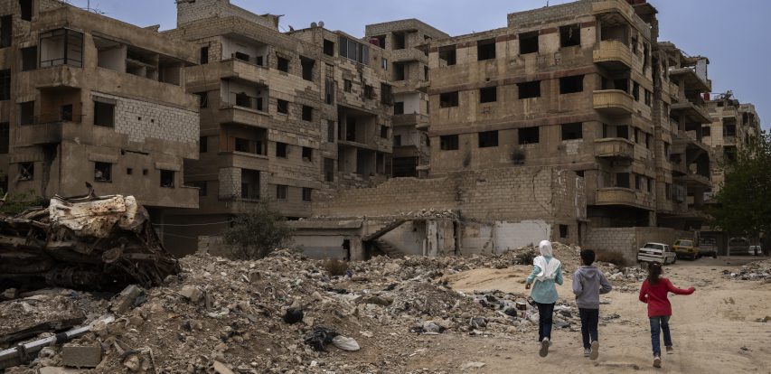 Kinder laufen durch Häusertrümmer in Syrien.