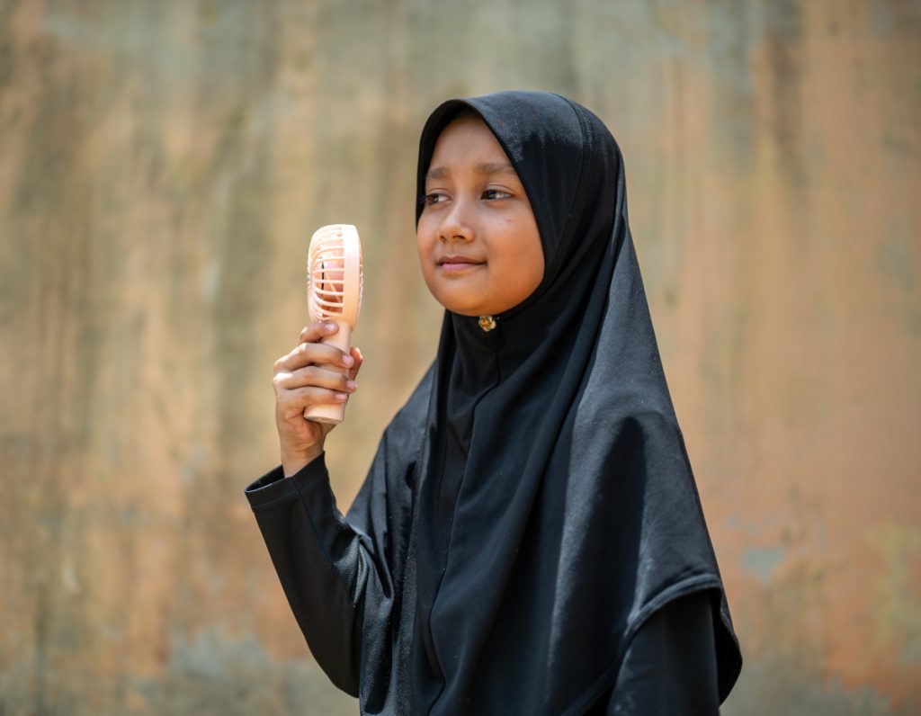 Mädchen in Malaysia hält einen kleinen Handventilator.