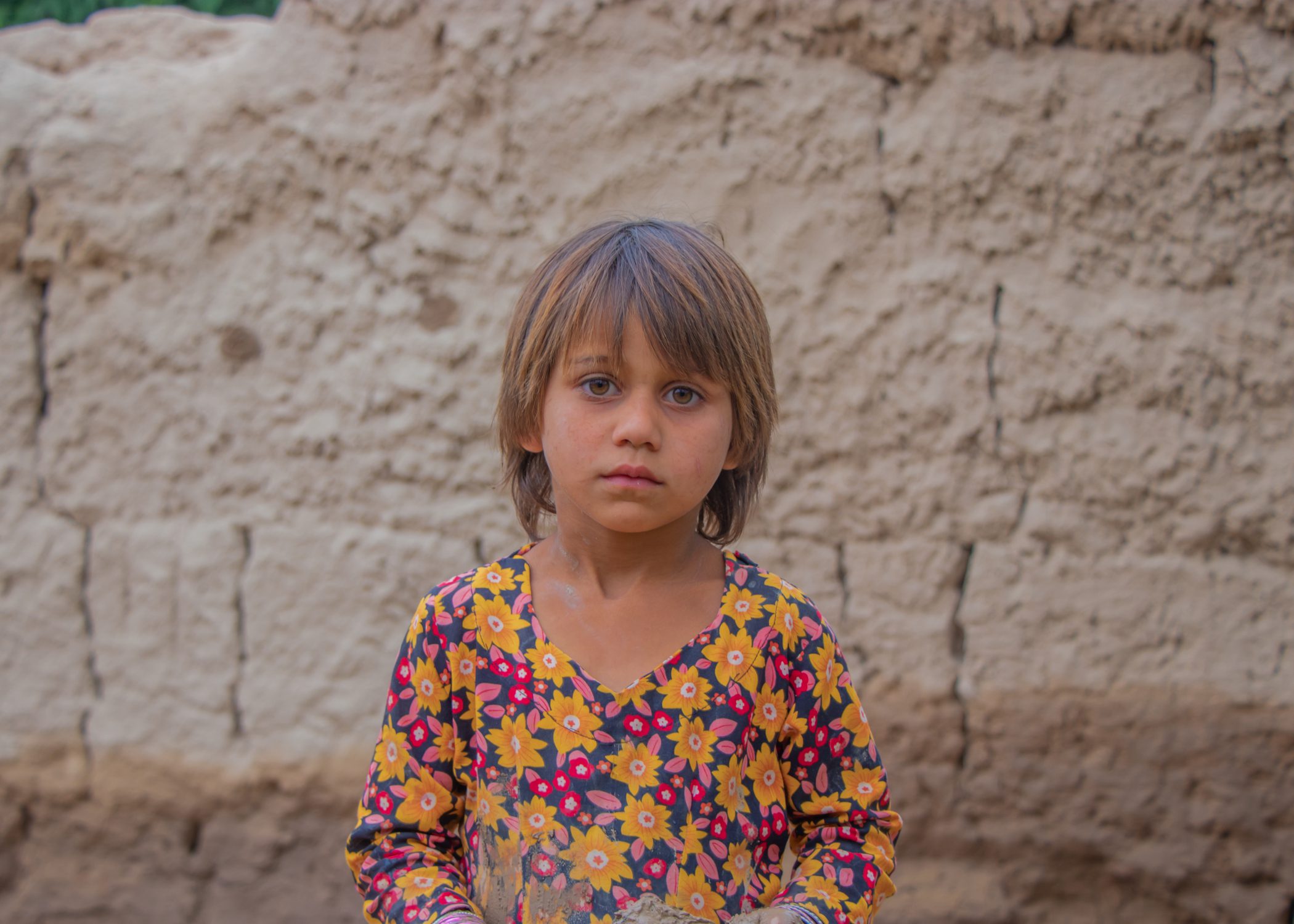 Mädchen in Afghanistan steht vor einer Wand.