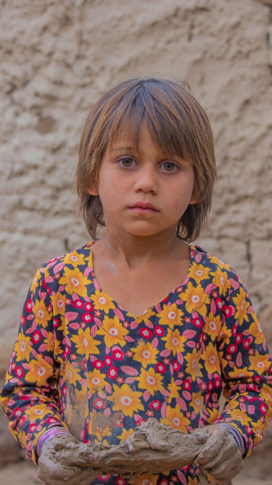 Mädchen in Afghanistan steht vor einer Wand.