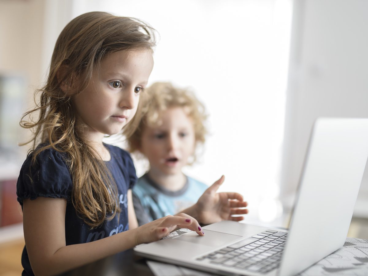 Zwei Kleinkinder schauen erstaunt in einen Laptop.