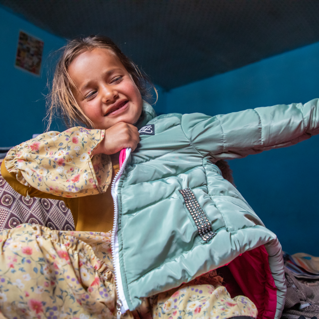 Mädchen in Afghanistan probiert eine Winterjacke an.