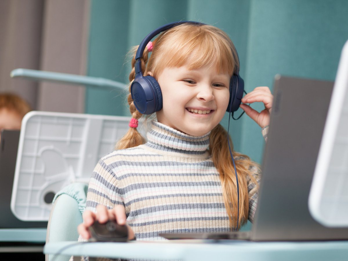 Mädchen mit Kopfhörern am Laptop.