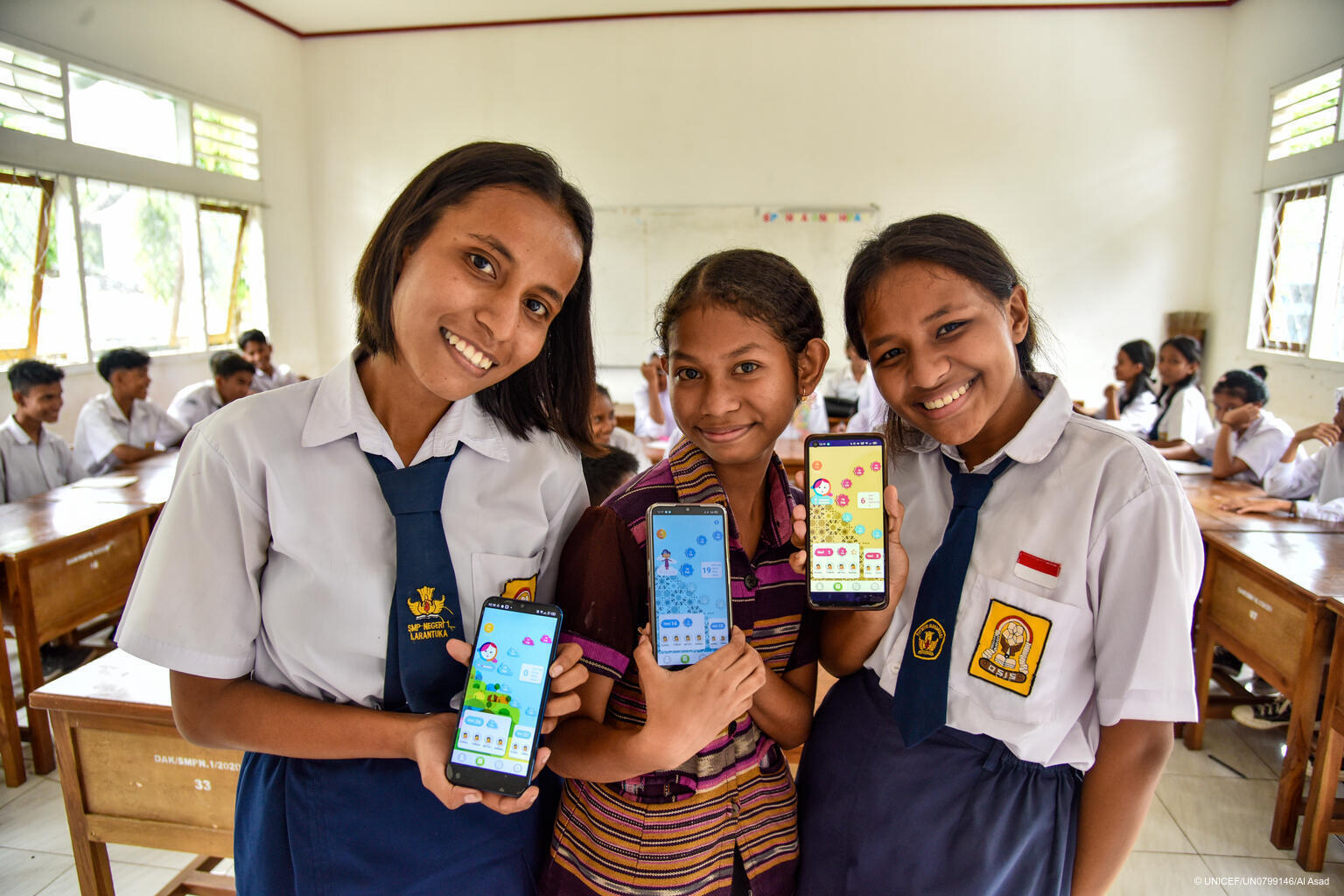 Drei Mädchen aus Indonesien zeigen die Oky App auf ihren Smartphones.