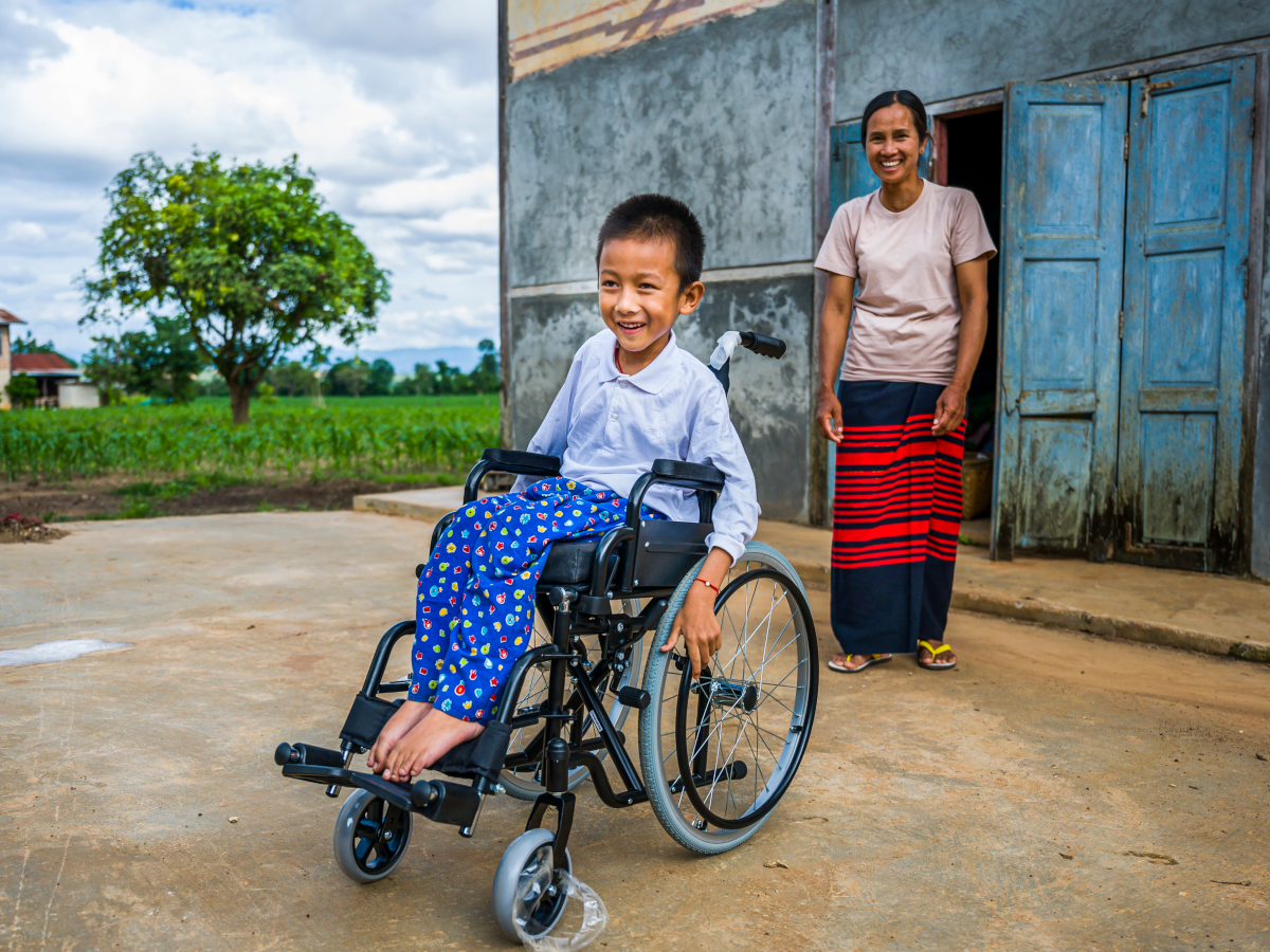 Junge im Rollstuhl vor seinem Haus in Myanmar.