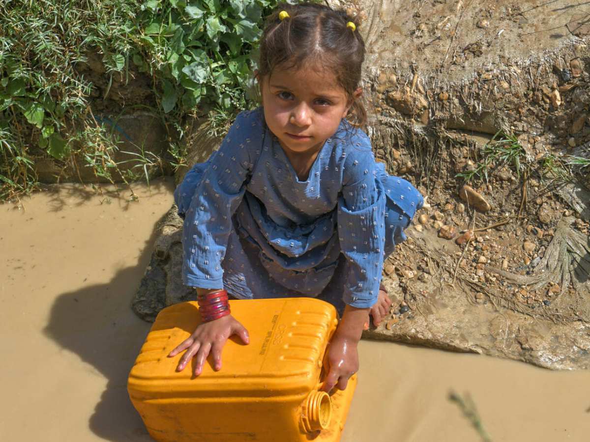 Mädchen füllt Kanister mit schmutzigen Wasser