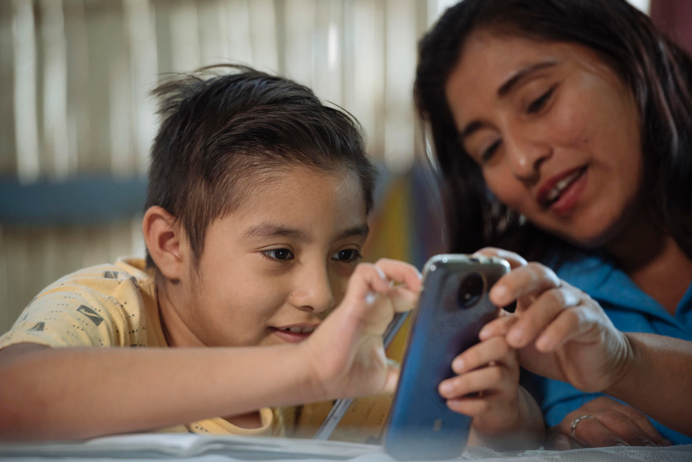 Eine Mutter in Ecuador zeigt ihrem Kinde etwas auf dem Smartphone.
