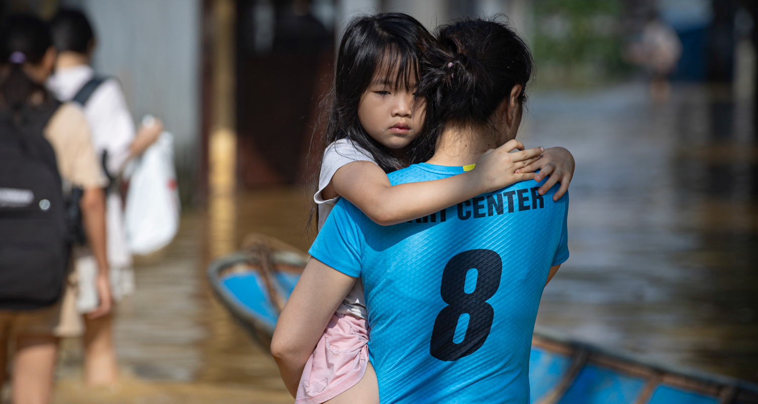 Frau hält Mädchen in einer Überschwemmung in Vietnam.