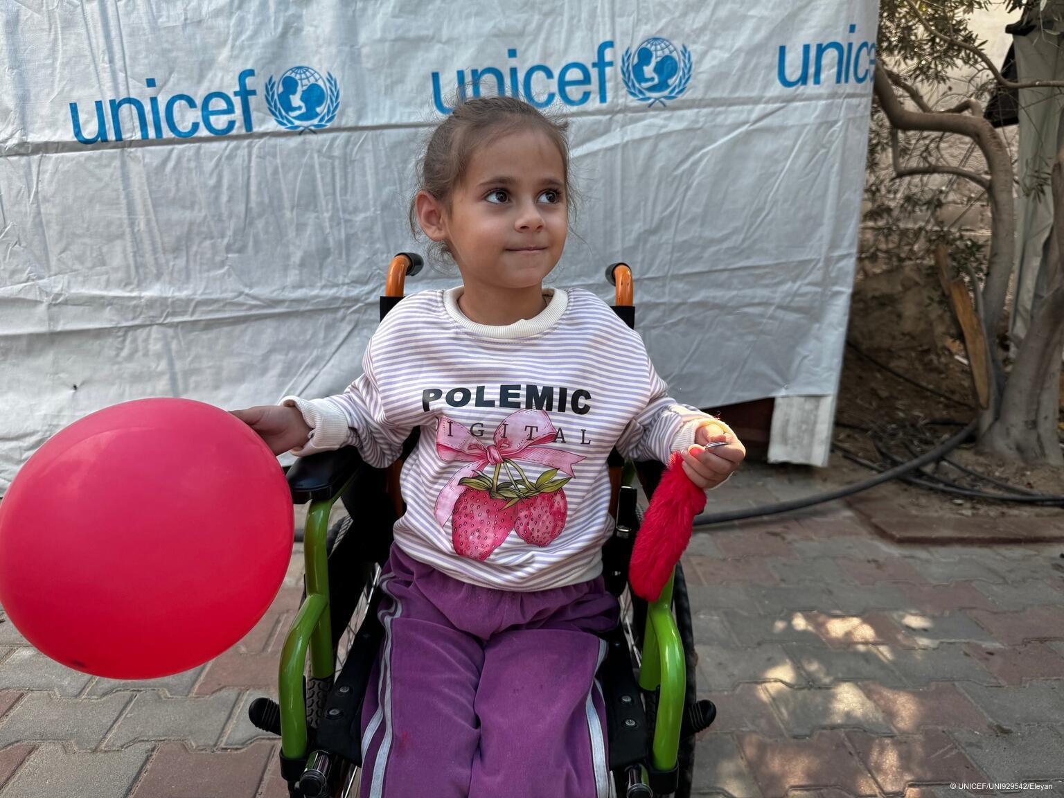 Ein Mädchen im Gazastreifen sitzt in einem Rollstuhl und hat einen Luftballon.
