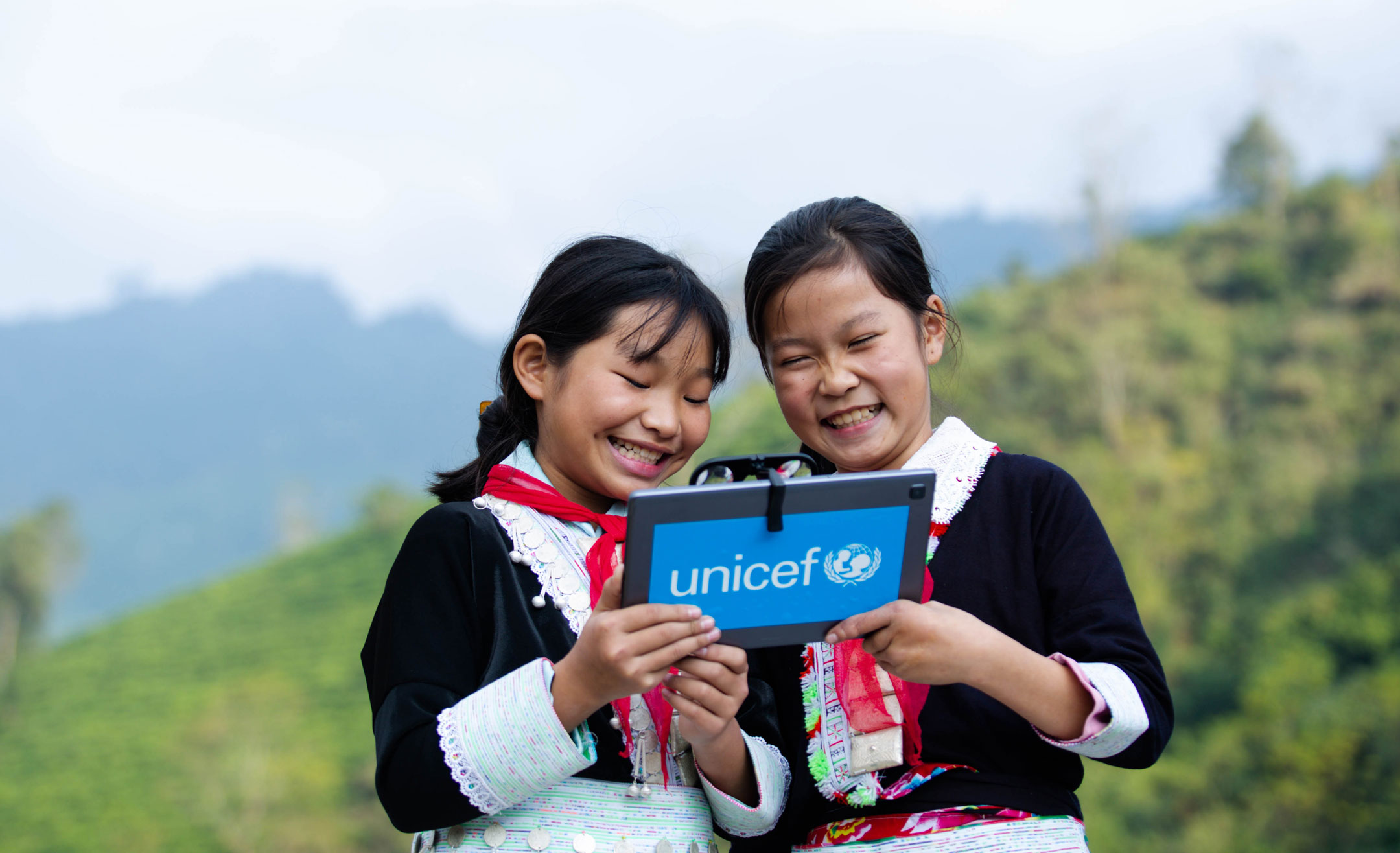 Zwei Mädchen haben ein Tablet in der Hand und lächeln