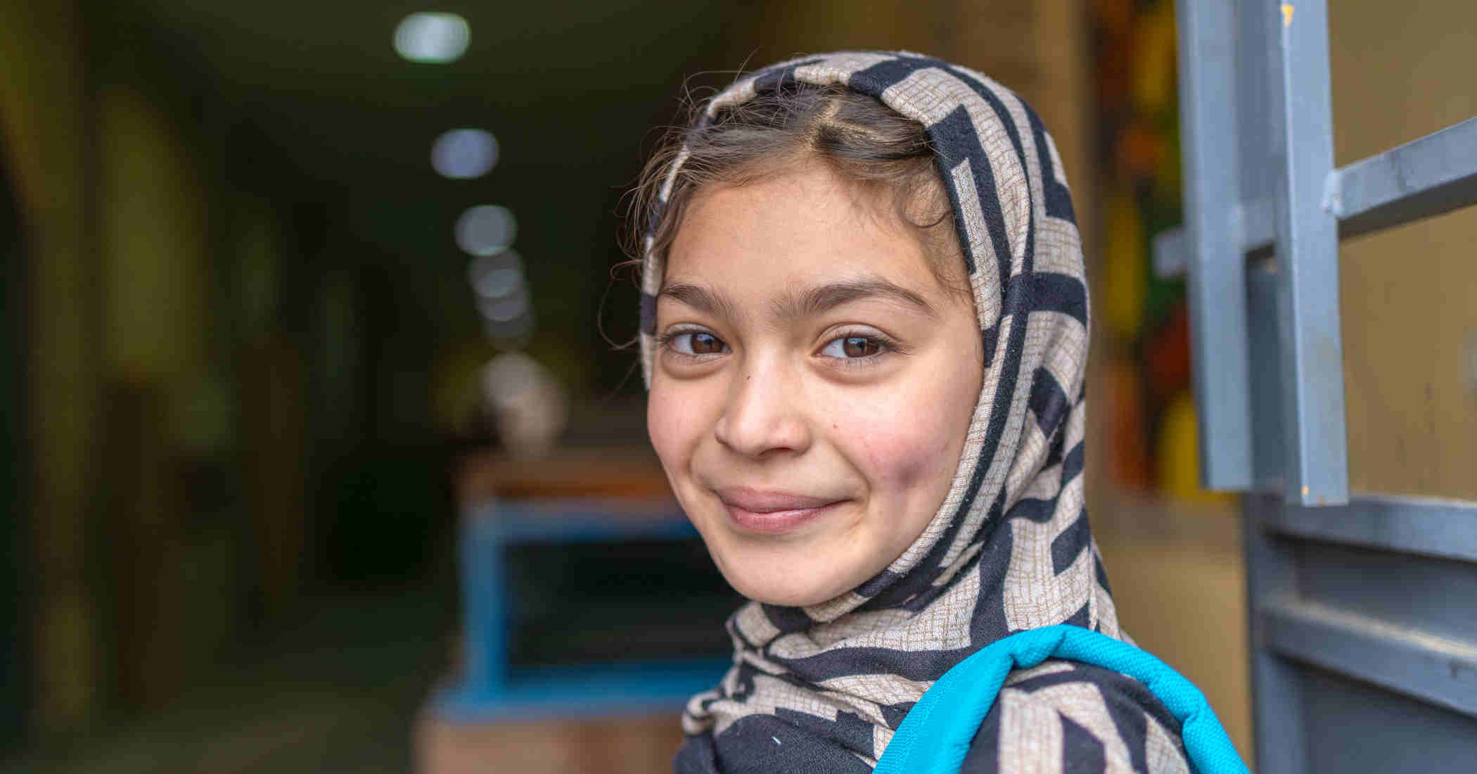 Lächelndes Mädchen mit Schultasche in Afghanistan.