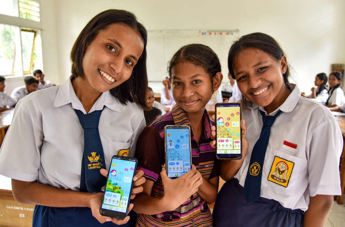 Drei Mädchen aus Indonesien zeigen die Oky App auf ihren Smartphones.