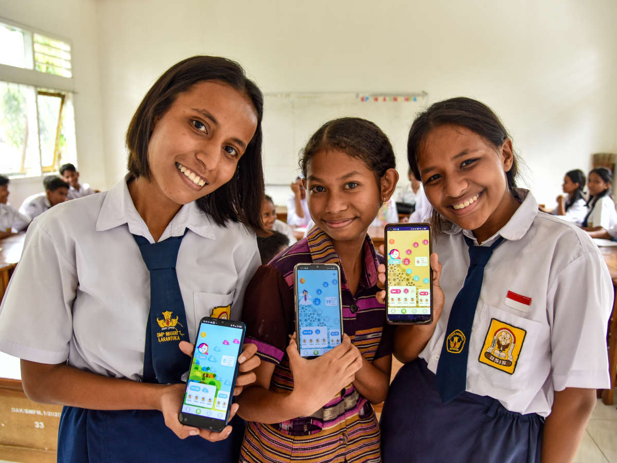 Drei Mädchen aus Indonesien zeigen die Oky App auf ihren Smartphones.