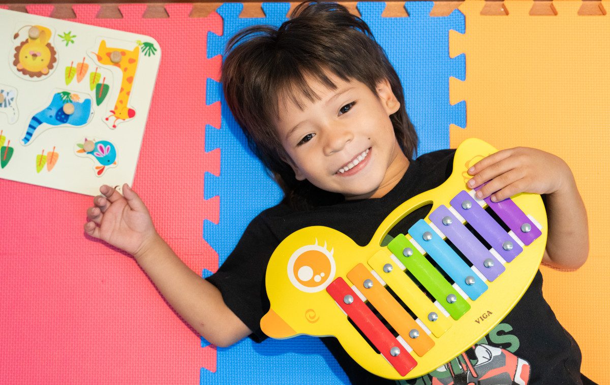 Junge spielt mit buntem Xylophon.