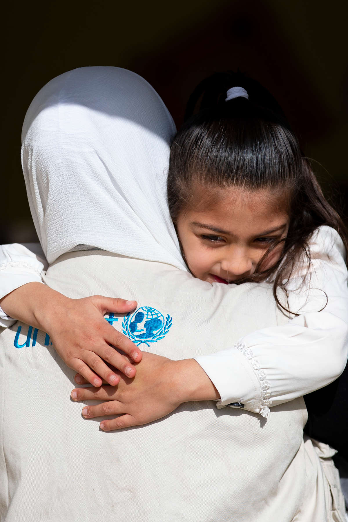 Mädchen wird von einer UNICEF-Mitarbeiterin gehalten.