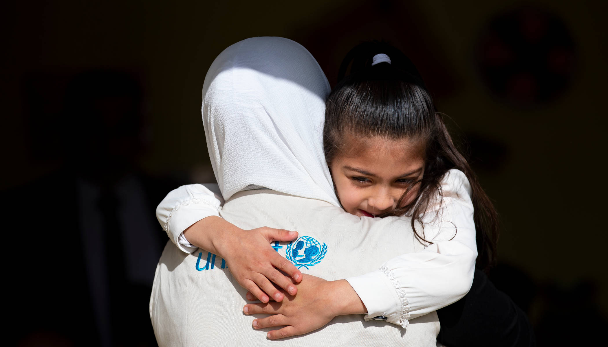 Mädchen wird von einer UNICEF-Mitarbeiterin gehalten.