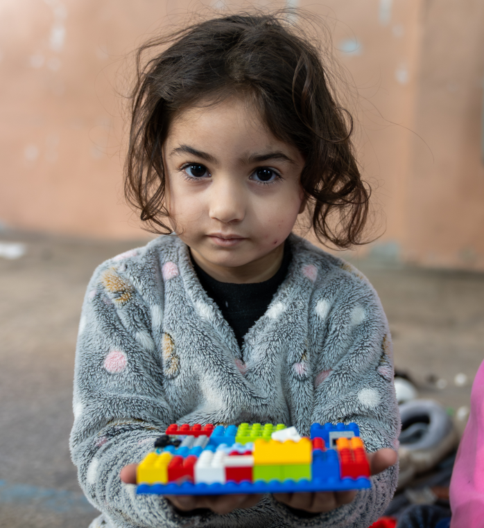 Mädchen hält Lego in einem Flüchtlingscamp im Libanon.