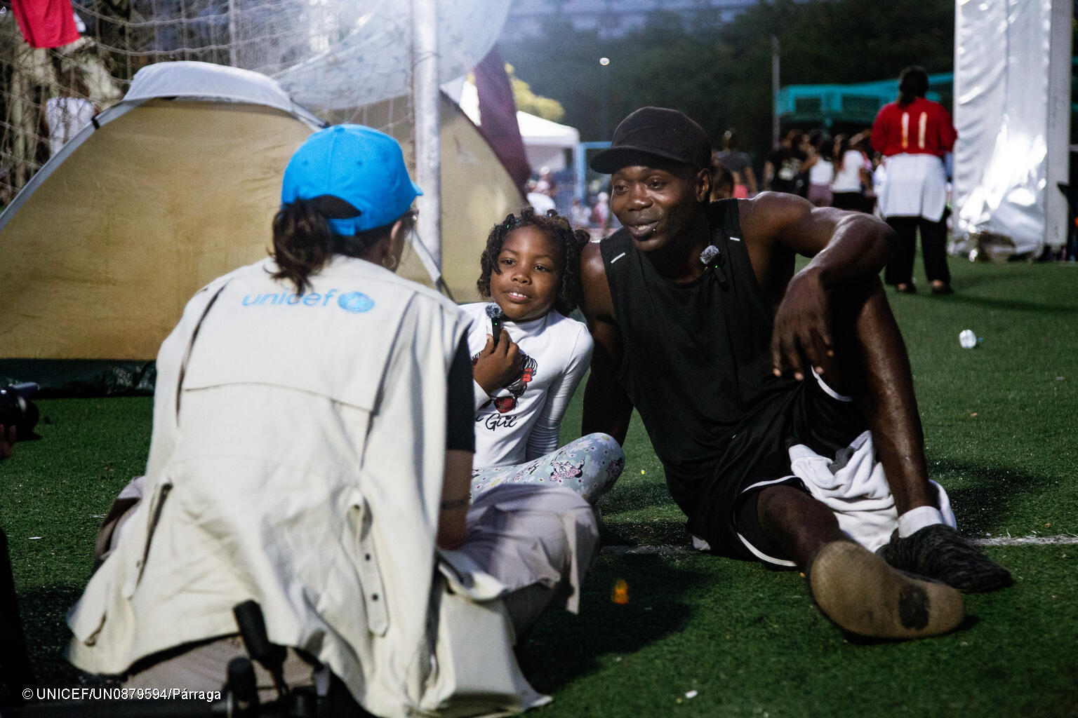 UNICEF Mitarbeiterin spricht mit Tochter und Vater in einer Notunterkunft.