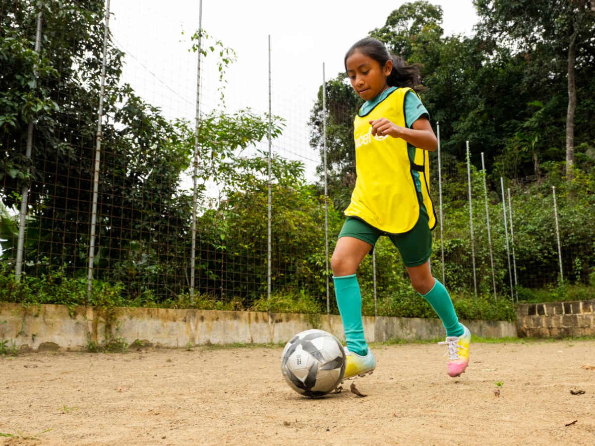 Mädchen dribbelt Fußball auf Platz.