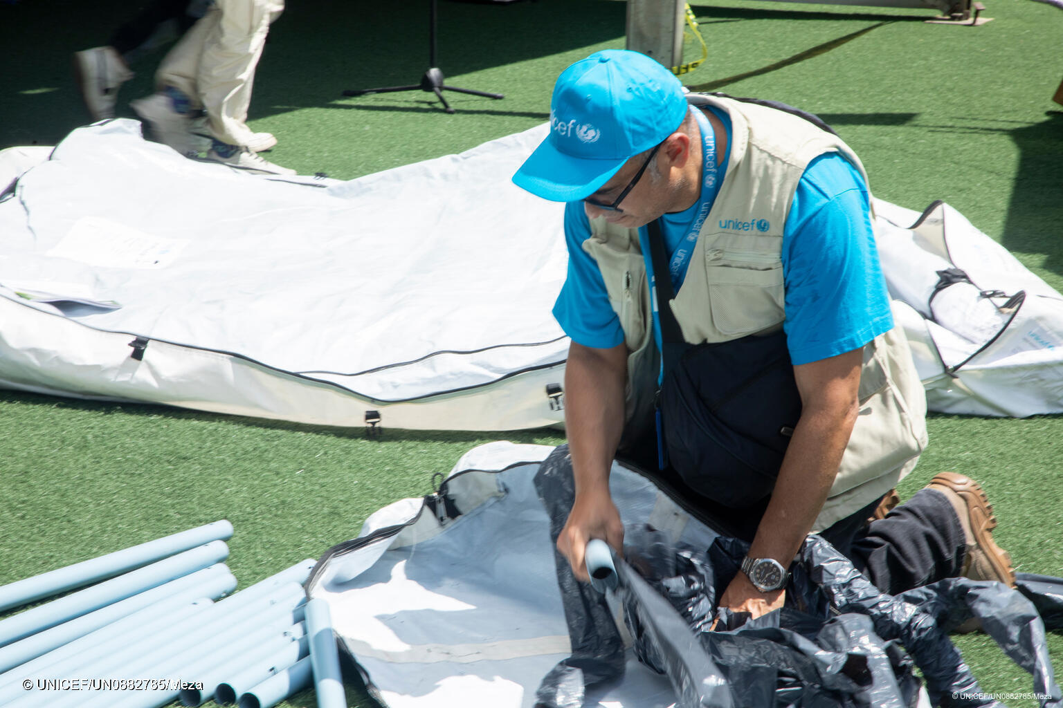 Ein UNICEF Mitarbeiter baut ein Zelt in einer Notunterkunft auf.