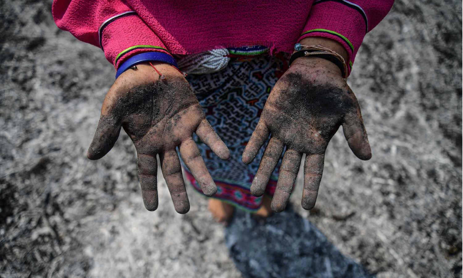 Mädchen mit Asche auf den Händen nach einem Waldbrand in Peru.