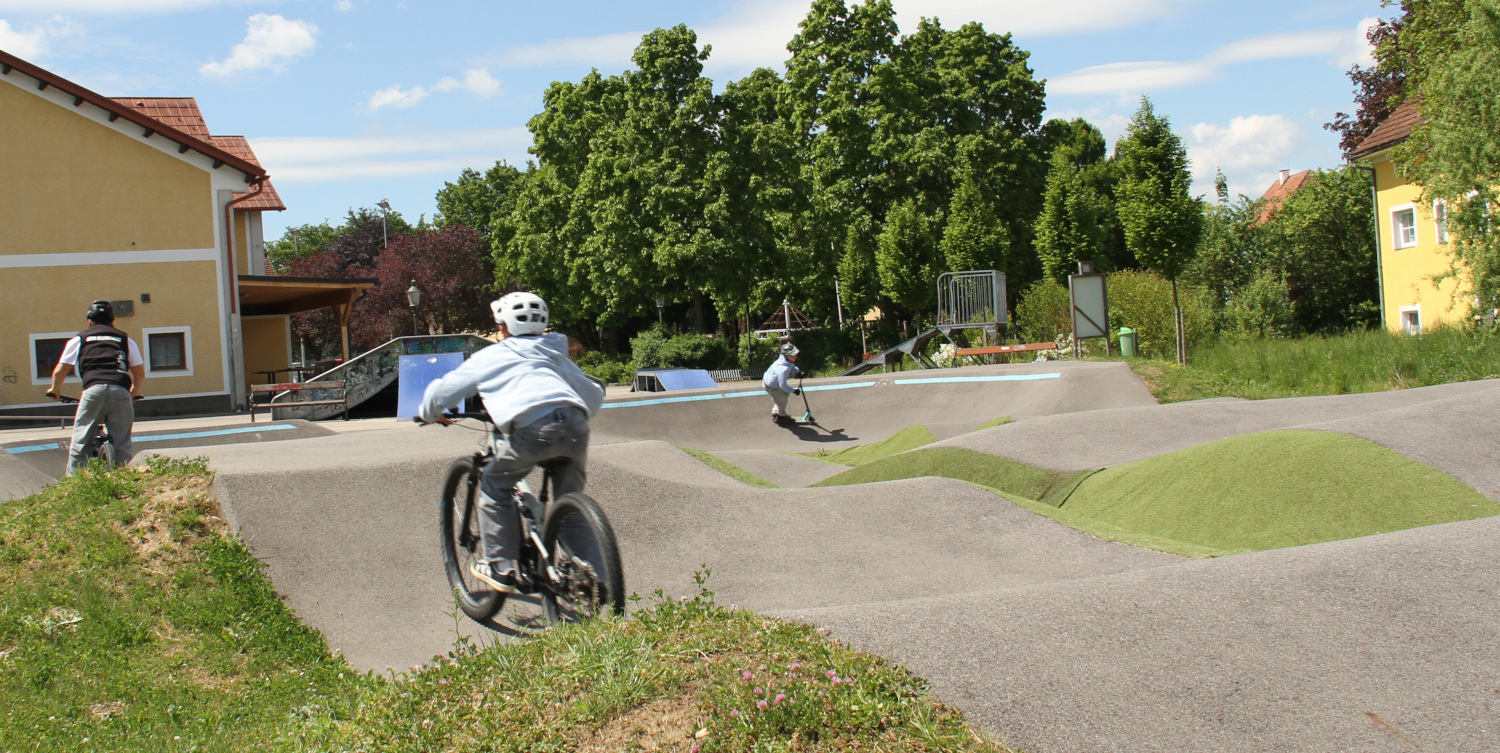 Kinder mit dem Fahrrad auf der Pumptrack-Strecke.