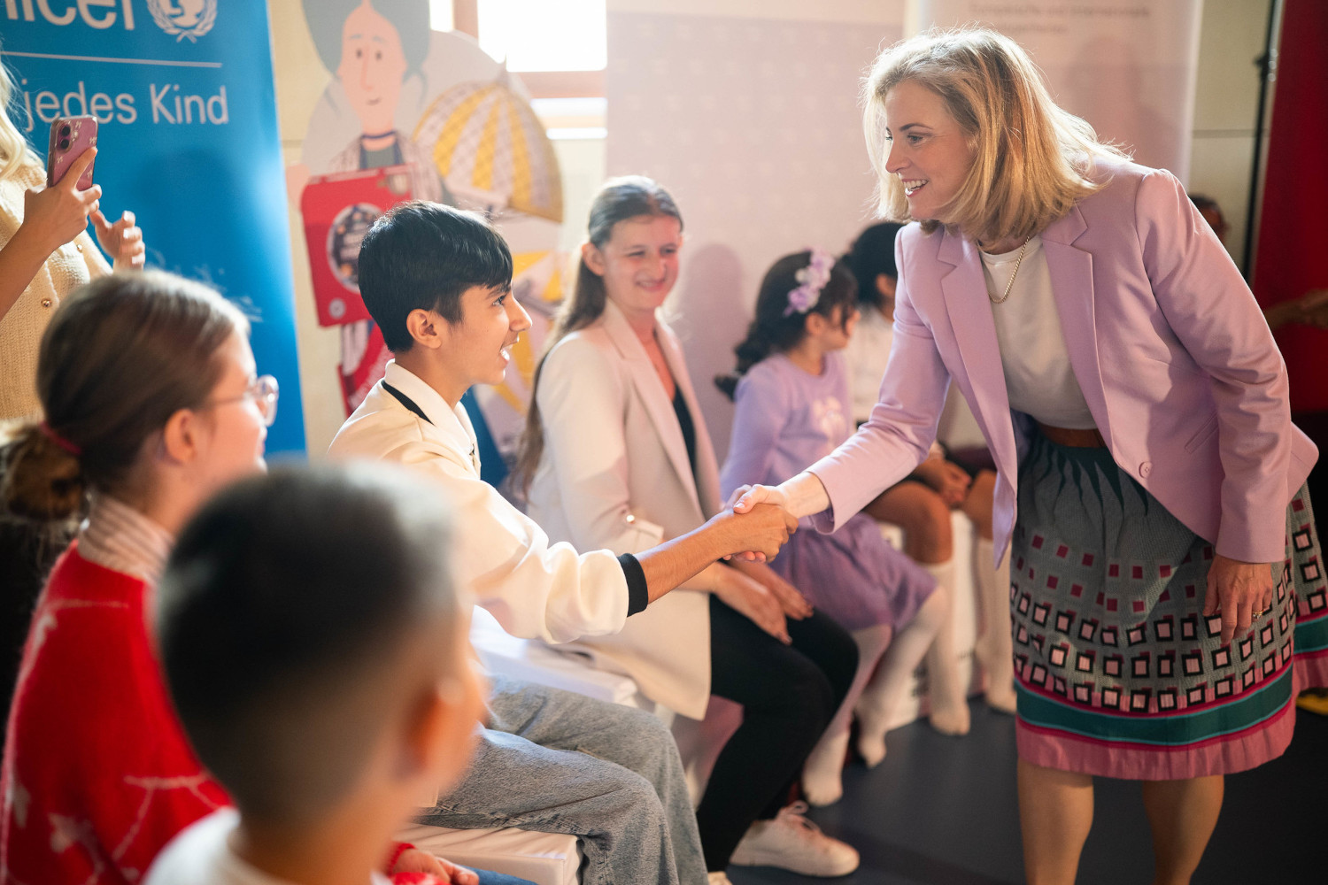 Außenministerin Beate Meinl-Reisinger begrüßt Kinder in der Schule.