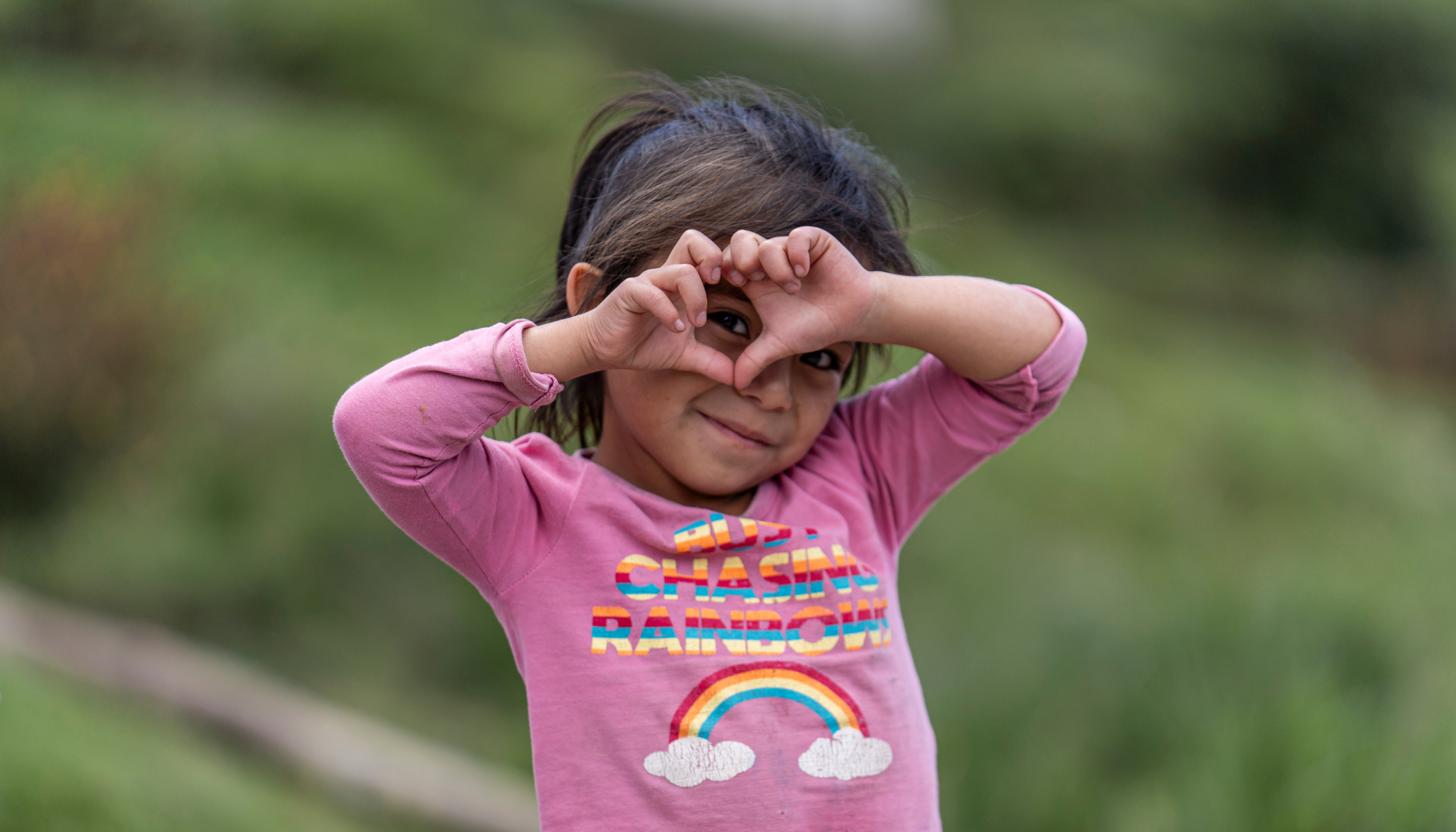 Mädchen aus Guatemala formt Herz mit Händen.